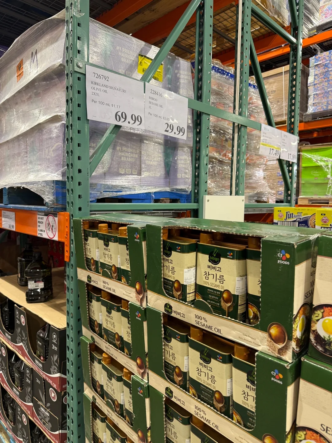 비비고 참기름 캔이 든 상자들과 위쪽 가격표. Kirkland Signature Olive Oil 2X3L 69.99, Bibigo Sesame Oil 1L 29.99라고 적혀 있다