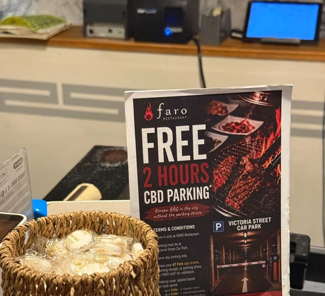 계산대 위에 세워 둔 Faro 안내판. FREE 2 HOURS CBD PARKING, Victoria Street Car Park와 이용 조건이 적혀 있다. 옆에 사탕이 담긴 바구니가 있다