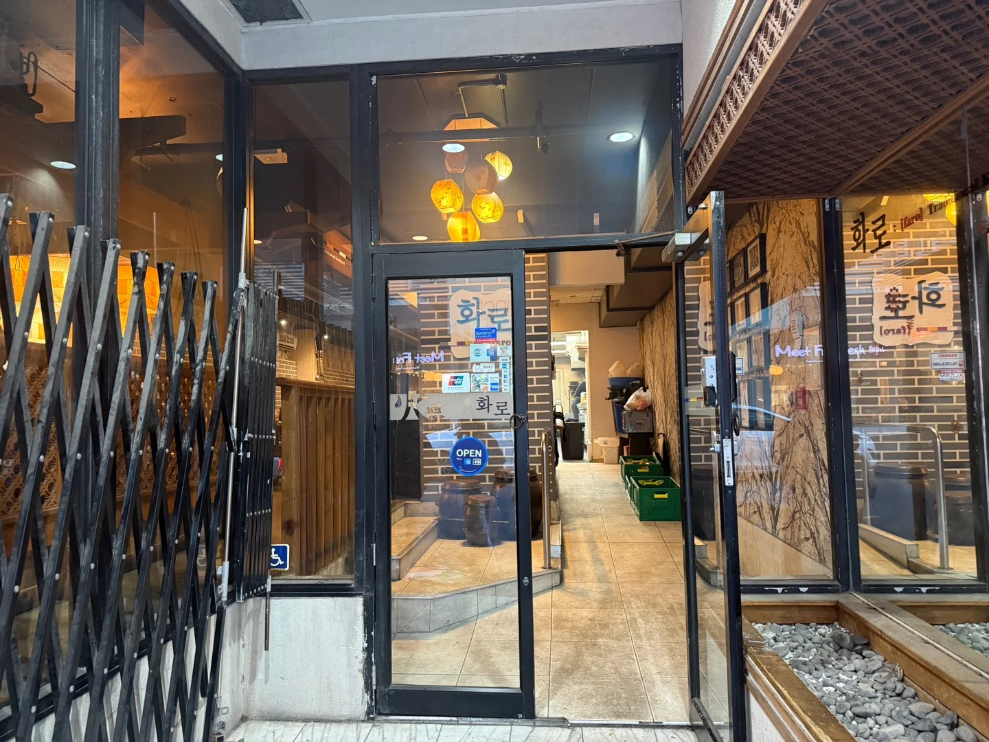 유리문과 유리창에 한글로 화로라고 적힌 식당 입구. 문에 OPEN 표시가 있고 안쪽에 장독이 놓여 있다
